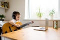 Concentrated boy in headphones plays guitar and watches online course on laptop while studying at home. Online training