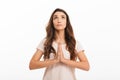 Concentrated brunette woman in t-shirt praying with pray gesture