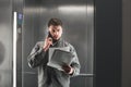 Concentrated businessman is talking on the smartphone and reading the documents in the lift. Concentrated male office worker Royalty Free Stock Photo