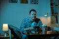 Concentrated caucasian man playing video game on a big screen and eating popcorn at home. Man holding wireless controller of a Royalty Free Stock Photo