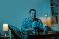 Concentrated caucasian man playing video game on a big screen and eating popcorn at home. Man holding wireless controller of a Royalty Free Stock Photo