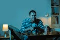 Concentrated caucasian man playing video game on a big screen and eating popcorn at home. Man holding wireless controller of a Royalty Free Stock Photo