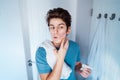 Concentrated caucasian teenage boy with acne problem take care his face skin at home. He looking in mirror and aplying Royalty Free Stock Photo