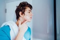 Concentrated caucasian teenage boy with acne problem take care his face skin at home. He looking in mirror and aplying Royalty Free Stock Photo