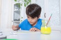 A concentrated child paints a piece of paper with a paintbrush during a craft