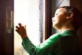 Concentrated child writes with his fingers on the foggy window