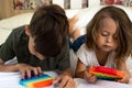 Concentrated children playing popit toys while lying on white bed.