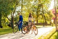 Concentrated couple of young cyclists is riding bicycles in the city park on a sunny summer day. Man and woman in colorful casual