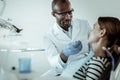 Concentrated dark-skinned doctor curing his female patient teeth