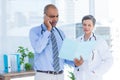 Concentrated doctor showing file to his colleague while calling