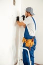 Concentrated electrician, handyman using screwdriver while working on installing socket on wall at home Royalty Free Stock Photo