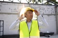 Concentrated engineer in safety vest at construction site wearing a hard helmet hat. Royalty Free Stock Photo