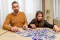 Concentrated father and daughter trying to put together a complicated puzzle of small pieces Royalty Free Stock Photo