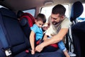 Concentrated father helps his son to fasten belt on car seat Royalty Free Stock Photo