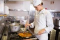 Concentrated female cook preparing food in kitchen Royalty Free Stock Photo