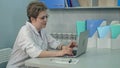 Concentrated female doctor in glasses typing on laptop in her office