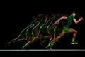 Concentrated and focused man, athlete in motion, running, training against black background with stroboscope effect