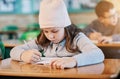 Concentrated on getting her schoolwork done. an elementary school girl doing school work in the classroom. Royalty Free Stock Photo