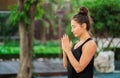 Concentrated girl sitting in lotus pose with hands in namaste and meditating or praying. Young woman with oriental Royalty Free Stock Photo