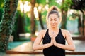 Concentrated girl sitting in lotus pose with hands in namaste and meditating or praying. Young woman with oriental Royalty Free Stock Photo