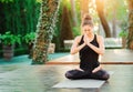 Concentrated girl sitting in lotus pose with hands in namaste and meditating or praying. Young woman with oriental Royalty Free Stock Photo