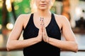 Concentrated girl sitting in lotus pose with hands in namaste and meditating or praying. Young woman with oriental Royalty Free Stock Photo