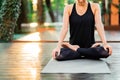 Concentrated girl sitting in lotus pose and meditating or praying. Young woman practicing yoga alone on wooden deck in Royalty Free Stock Photo