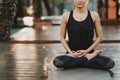 Concentrated girl sitting in lotus pose and meditating or praying. Young woman practicing yoga alone on wooden deck in Royalty Free Stock Photo