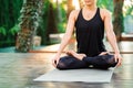 Concentrated girl sitting in lotus pose and meditating or praying. Young woman practicing yoga alone on wooden deck in Royalty Free Stock Photo