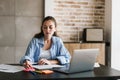 Concentrated girl using laptop computer while writing notes Royalty Free Stock Photo