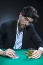 Concentrated Handsome Caucasian Brunet Pocker Player At Pocker Table With Chips While Dealing Cards and Drinking Alcohol