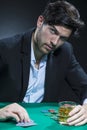 Concentrated Handsome Caucasian Brunet Pocker Player At Pocker Table With Chips While Dealing Cards and Drinking Alcohol