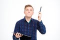 Concentrated handsome man holding clipboard and pointing up by pen Royalty Free Stock Photo