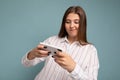 Concentrated happy attractive young blonde woman wearing casual white shirt isolated over blue background wall holding