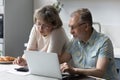 Concentrated happy older couple managing household budget.