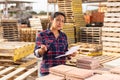 Female worker checking quantity of paving slabs in warehouse