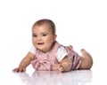 Focused infant baby girl toddler in polka dot dress is lying on stomach holding arm outstretched going to get something