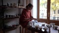 Concentrated introverted woman working alone sits at table in pottery making original crockery