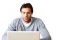 Concentrated on keeping connected. A handsome man sitting and working on a laptop against a white background.