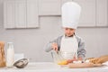 concentrated kid in chef hat whisking eggs in bowl at table Royalty Free Stock Photo