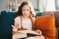 Concentrated kid girl reading interesting book at home Royalty Free Stock Photo