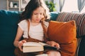 Concentrated kid girl reading interesting book at home Royalty Free Stock Photo