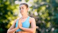 Concentrated lady yoga practitioner in blue top meditates standing in position with closed eyes
