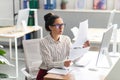 Concentrated latin businesswoman working with documents and reports, sitting at workplace in office interior Royalty Free Stock Photo