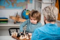 Concentrated little boy - father and son sitting at the table and playing chess. Teacher and schoolboy playing chess in Royalty Free Stock Photo