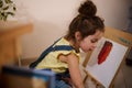 Concentrated little European pretty baby girl in yellow t-shirt and blue denim drawing picture at home, using watercolor paints, Royalty Free Stock Photo