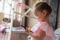 Concentrated little girl child indoors using mobile phone.