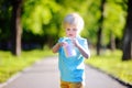 Concentrated little kid boy drawing with colored chalk on asphalt