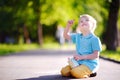 Concentrated little kid boy sitting and drawing with colored chalk on asphalt