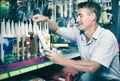 Concentrated man customer choosing sealant tube in hypermarket